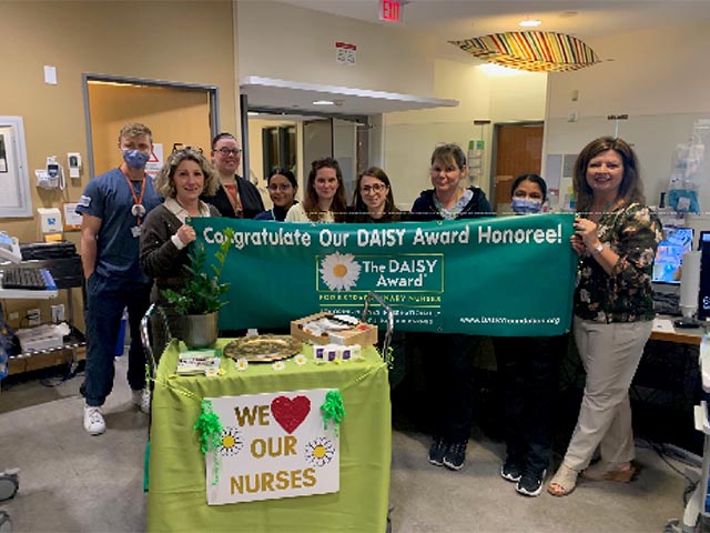 A group of nurses and hospital staffs holding a banner saying "congratulate our Daisy Award honoree!