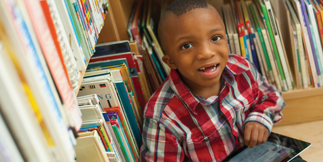 Little boy with computer tablet in a library.