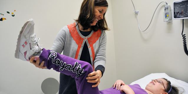 Staff helping a girl raise her leg.