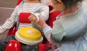 2 children interacting holding hands with communication aid