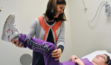 Female staff member helping a girl lift her leg