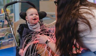 A baby with smile sitting on a stroller