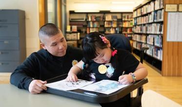 An adult and a child in a library setting