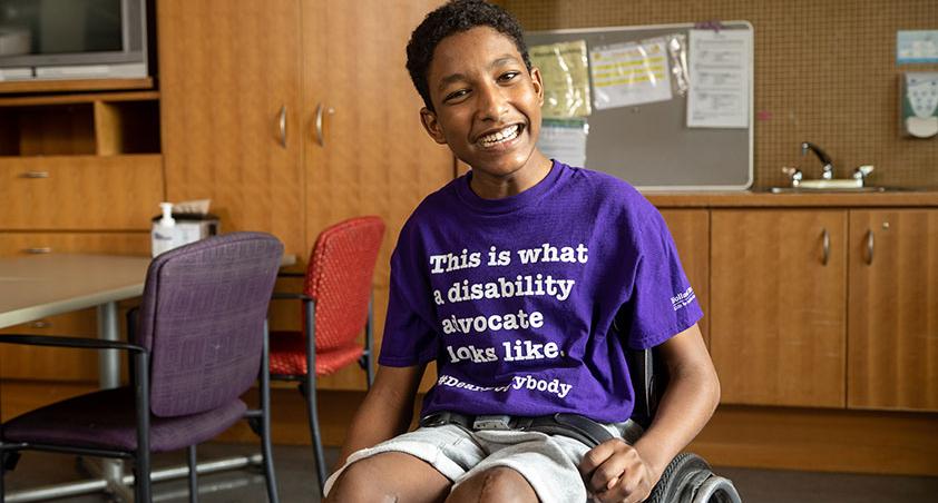 A child sitting on wheelchair with smile on face