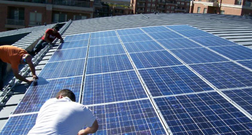 Three people installing solar panels on the roof