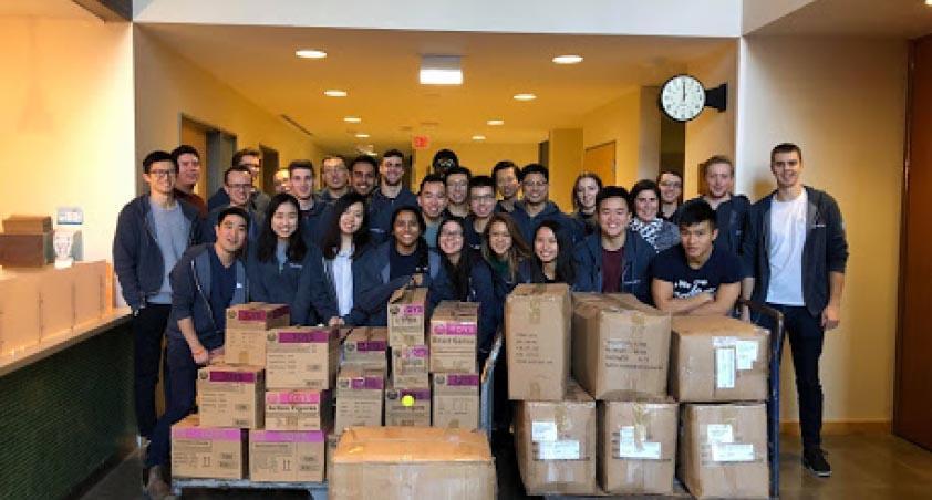 Group photos of people with some boxes in front, with an indoor setting