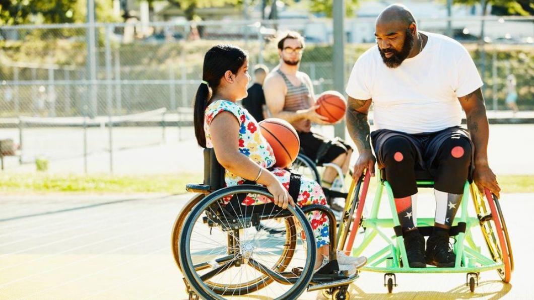 Man and girl in wheelchairs playing basketball