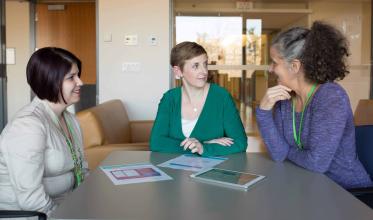 Three women discussing at a table 