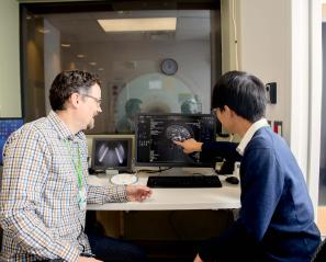 Two adults looking at an image of a brain scan on a computer screen