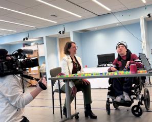 reporter with a camera is filming a clinician and a teen using brain computer interface