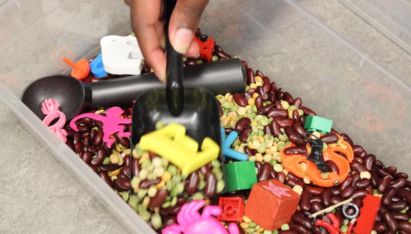 A bucket of beans and knick knacks that Rashan Edwards uses as a sandbox search activity. 