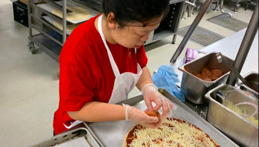 A student making pizza. 