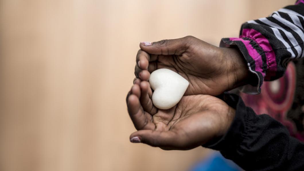 a woman's hands hold a small clay heart