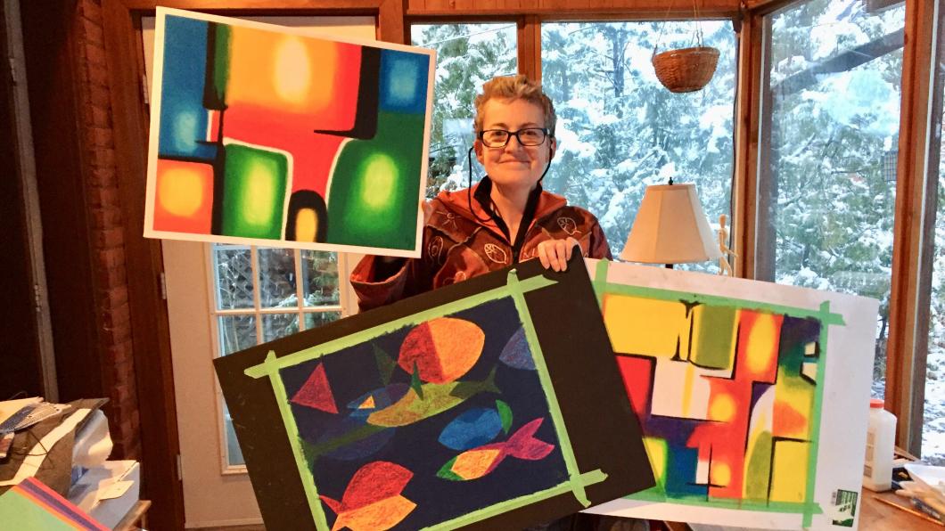 Woman holding bright abstract paintings