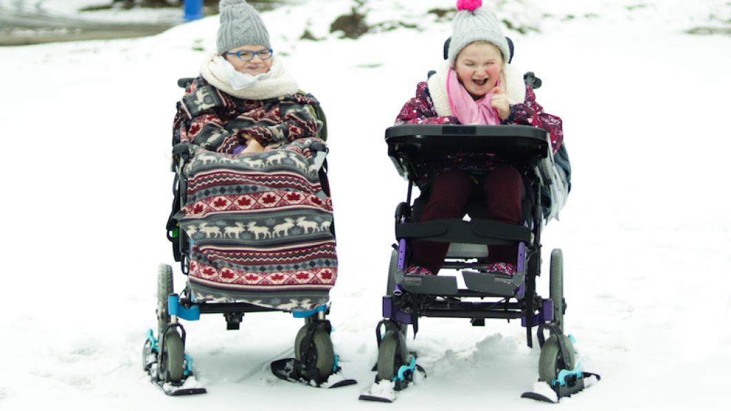 Girls in wheelchairs with mini skis under the wheels